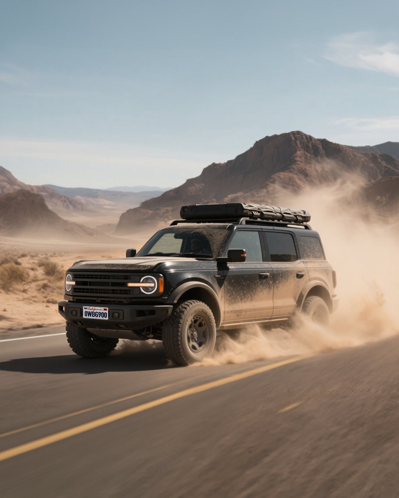 Black SUV driving on a desert road with mountains in the background